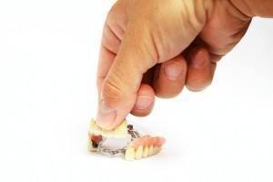 Photo of hand holding tiny set of dentures.
