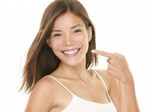Dental teeth - perfect smile woman pointing at teeth whitening results