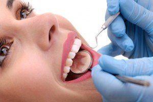 Woman having her gums and teeth cleaned and examined.