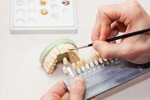 Dentist carefully painting model teeth as part of restorative dentistry services