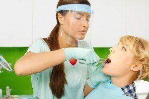 Dentist with masking preparing to do tooth extraction on a patient