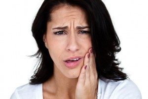 Woman with tooth pain pressing her hands on cheek looking for emergency dentist